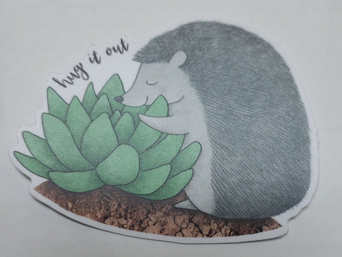 Vinyl sticker of "Hug it Out". Hedgehog is hugging a catcus plant. Perfect for your laptop, mirror or waterbottle.