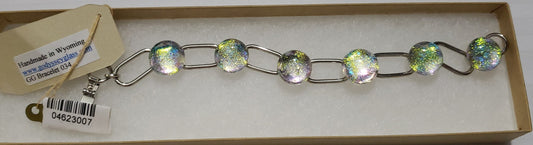 Dichroic Glass Bracelet Artist: Leslie Irving  6 clear/yellow/blue dichroic glass stones on silver plated long link chain setting  7" long  Please note items are custom made by artist   034  09-2023 updated inventory  number to LGI2059 $48 to 046-23007