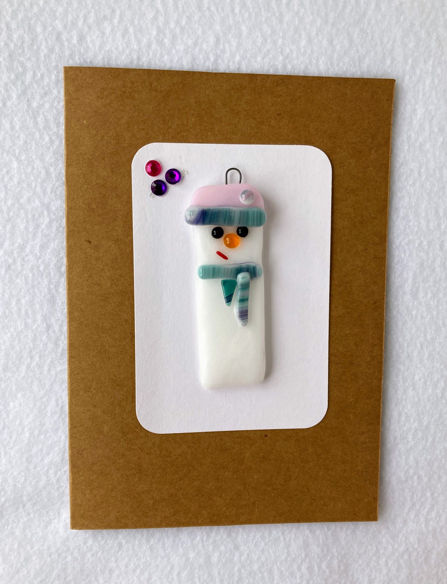 Fused Glass Christmas Ornament Snowman with pink hat and purple stripe Green and purple striped scarf 2' wide 2' long 0.25 high ornament Included is a 5" x 7" blank Kraft paper card with envelope