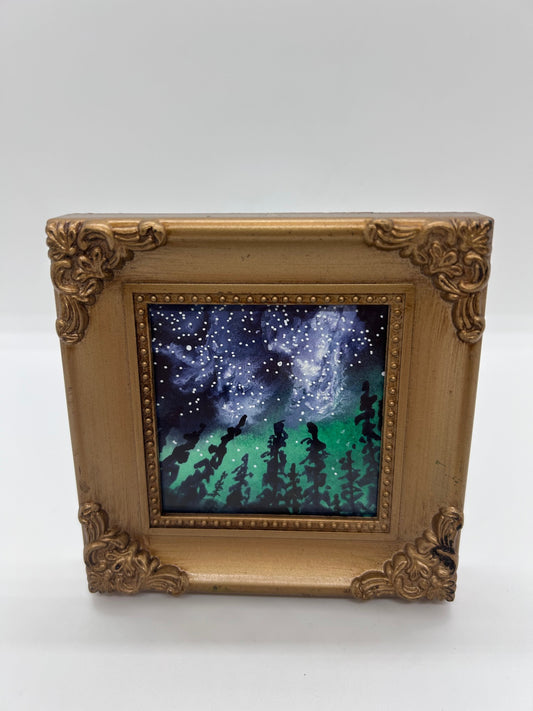 Original miniature watercolor and Ink   Star filled night sky above the black outline of the pine tree forest  The night sky is full of colors of the Aurora Borealis&nbsp;   Framed in a gold colored resin frame   Easel back allows to display on a table or shelf   4" long x 4" high x .5" wide   Signed by the artist