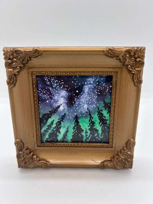 Original miniature watercolor and Ink   Just envision yourself camping in the Snowy Range Mountains   If you look up toward the night sky you will see the Milky Way outlined by the towering pine trees of the forest  This original painting also shows the night sky full of colors of the Aurora Borealis&nbsp;  Framed in a gold colored resin frame   Easel back allows to display on a table or shelf   4" long x 4" high x .5" wide   Signed by the artist
