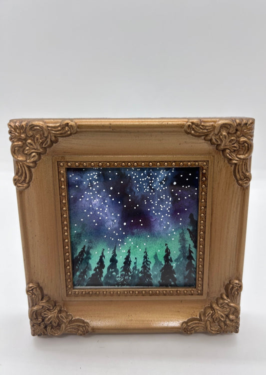 Original miniature watercolor and Ink   A forest of pine trees stand in shadow in front of a Wyoming star filled sky   The night sky has colors of the Aurora Borealis&nbsp;  Framed in a gold colored resin frame   Easel back allows to display on a table or shelf   4" long x 4" high x .5" wide   Signed by the artist