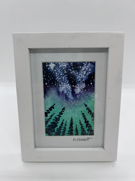 Original miniature watercolor and Ink   The Milky Way Galaxy shines bright in the night sky above pine trees   Aurora adds color to the night sky  Framed in a white wooden frame  Easel back allows to display on a table or shelf   3.75" long x 4.75" high x .5" wide   Signed by the artist
