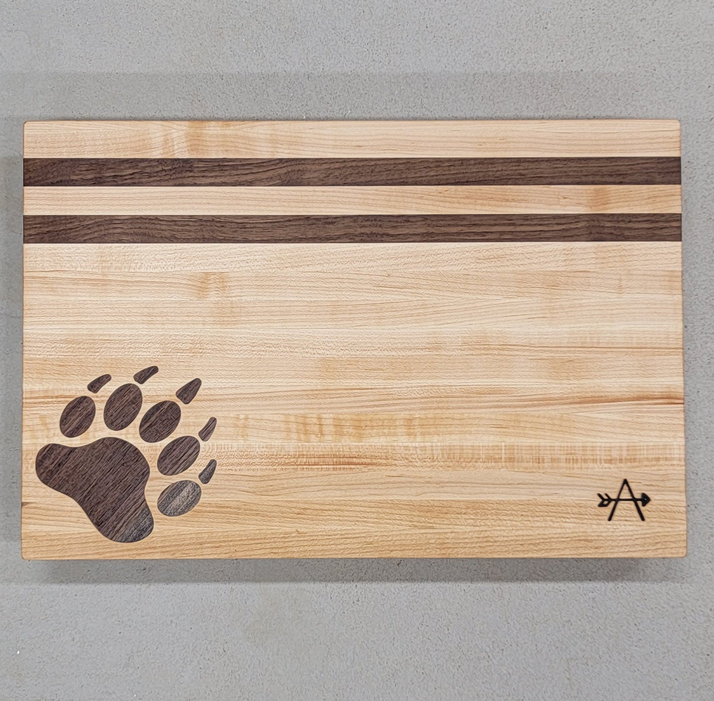" Bear " Maple and Walnut Wood Cutting Board
Artist: Kevin Shimkus
Edge-grain cutting board made of walnut and maple
Bear print inlay in lower left corner
Two walnut stripes at the top of a maple board
Four small feet on bottom side of cutting board to prevent slipping
WoW your guests with this beautiful, handcrafted charcuterie board.
This is a keepsake to hand down for generations!