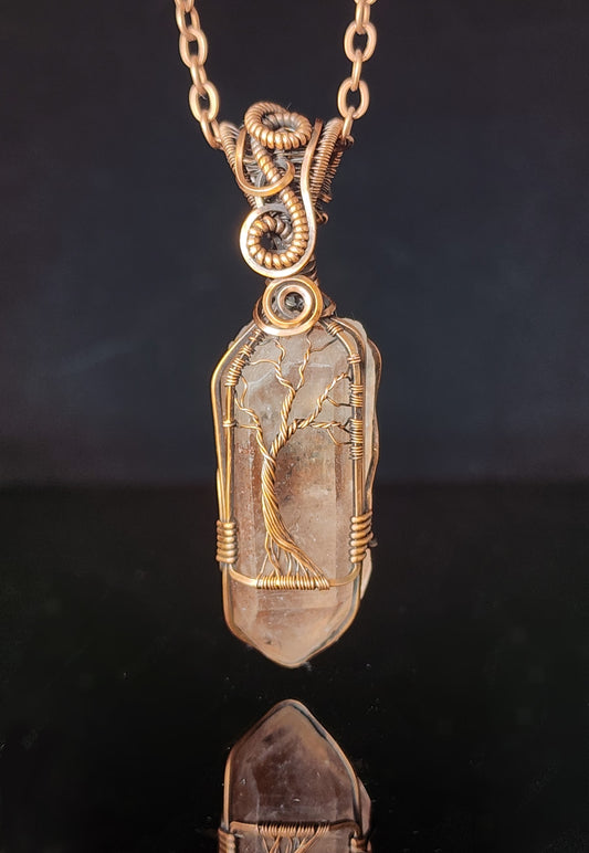 Rocky Mountain lithium quartz crystal in oxidized copper  The Rocky Mountain lithium quartz crystal was hand dug by the artist and hand wrapped in the copper wire  Wire wrapping creates the Tree of Life around the crystal  2.18" Long x .63" Wide  Copper chain with lobster clasp closure  A truly one-of-a-kind piece of jewelry  Care instructions with polishing cloth included