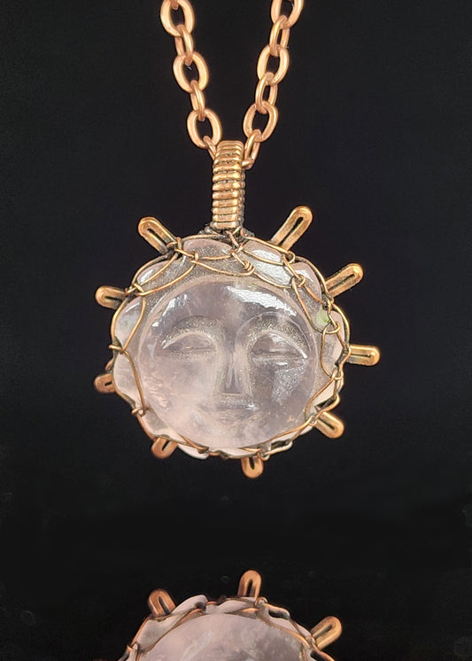 Carved sun face in Rose Quartz and wrapped in oxidized copper wire to look like the sun  1.19" Long x 1.02" Wide  Copper chain with lobster clasp closure  A truly one-of-a-kind piece of jewelry  Care instructions with polishing cloth included  Unique piece to brighten someone's day