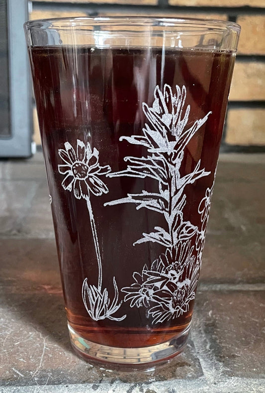 A pint glass engraved with a series of native Wyoming wildflowers