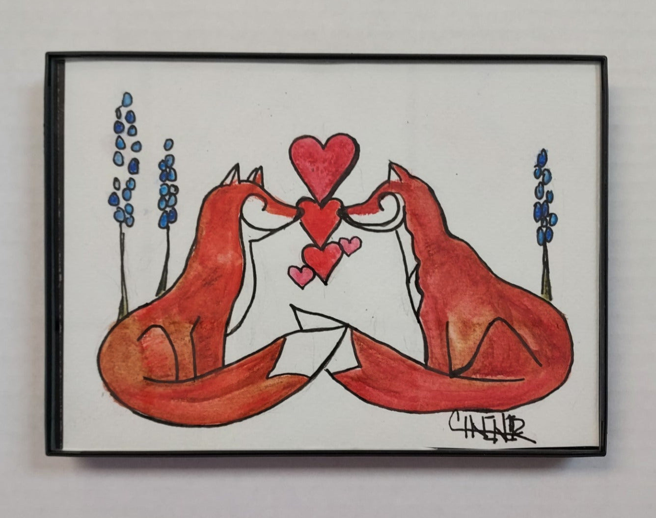 " Fox Love and Delphinium " Framed Original Watercolor and Ink Artist: Celeste Havener Original watercolor and ink drawing Two fox with hearts between them standing next to blue delphinium flowers Framed in sleek black plastic frame Can be hung on a wall or use the frames easel back to set on a table Would make a great wedding or anniversary gift 7" long x 5" high x 1/2" deep