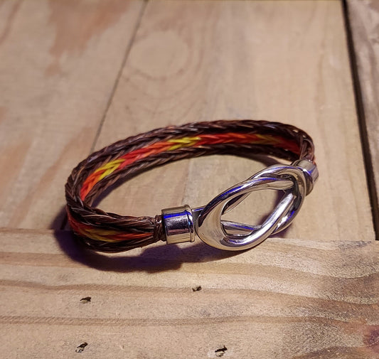 hand braided horsehair bracelet in brown with dyed  red, orange and yellow hair with magnetic infinity knot clasp
