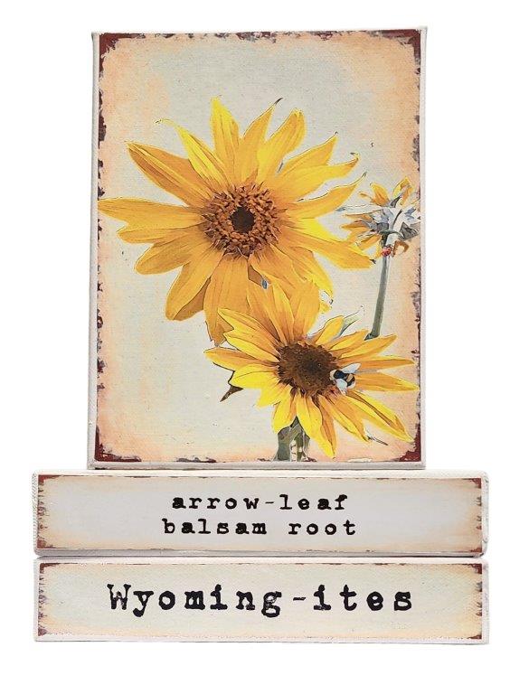 " Arrow Leaf Balsam Root Wyoming-ites" Canvas Print Artist: Catherine Holt Print on canvas with wooden framework Copy from artists original artwork Arrow leaf flower with bumble bees Arrow Leaf Balsam Root label on one side and Wyoming-ites label on the other Wyoming-ites is a series of "life in Wyoming" lifestyles and experiences! 6" long x 8" high x 1 1/2" wide Signed and numbered by the artist