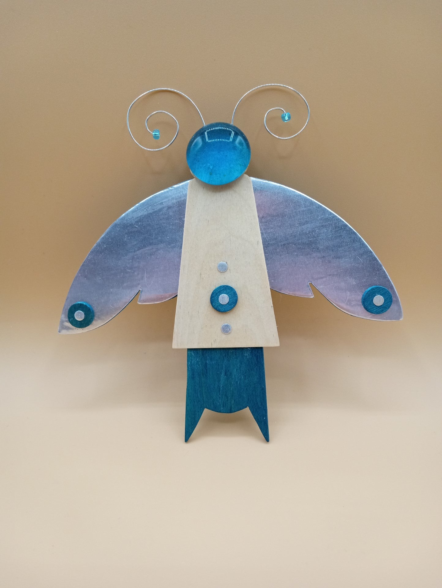 Blue wood body with metal coated wings Metal wire antennae Blue glass bead head. Blue wood body with metal coated wings Metal wire antennae Blue glass bead head 7" long x 7" wide x 1/2" high Wonderful year around decoration Great for any insect enthusiast Wire hanger on back