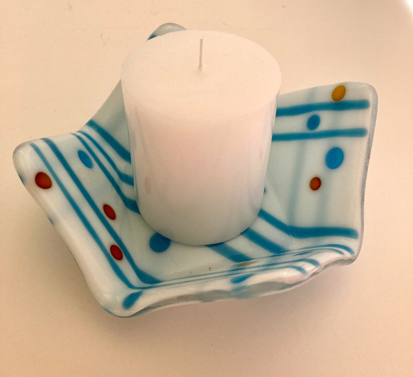 Fused glass dish Fun shaped white dish with light blue stripes and dots of blue, orange and gold color Use as a candy dish or to hold other small items like a candle A candle can sit in the dish, or turn dish over and place candle on top (when using a candle always place in a safe location, and protect furniture from dripping wax)