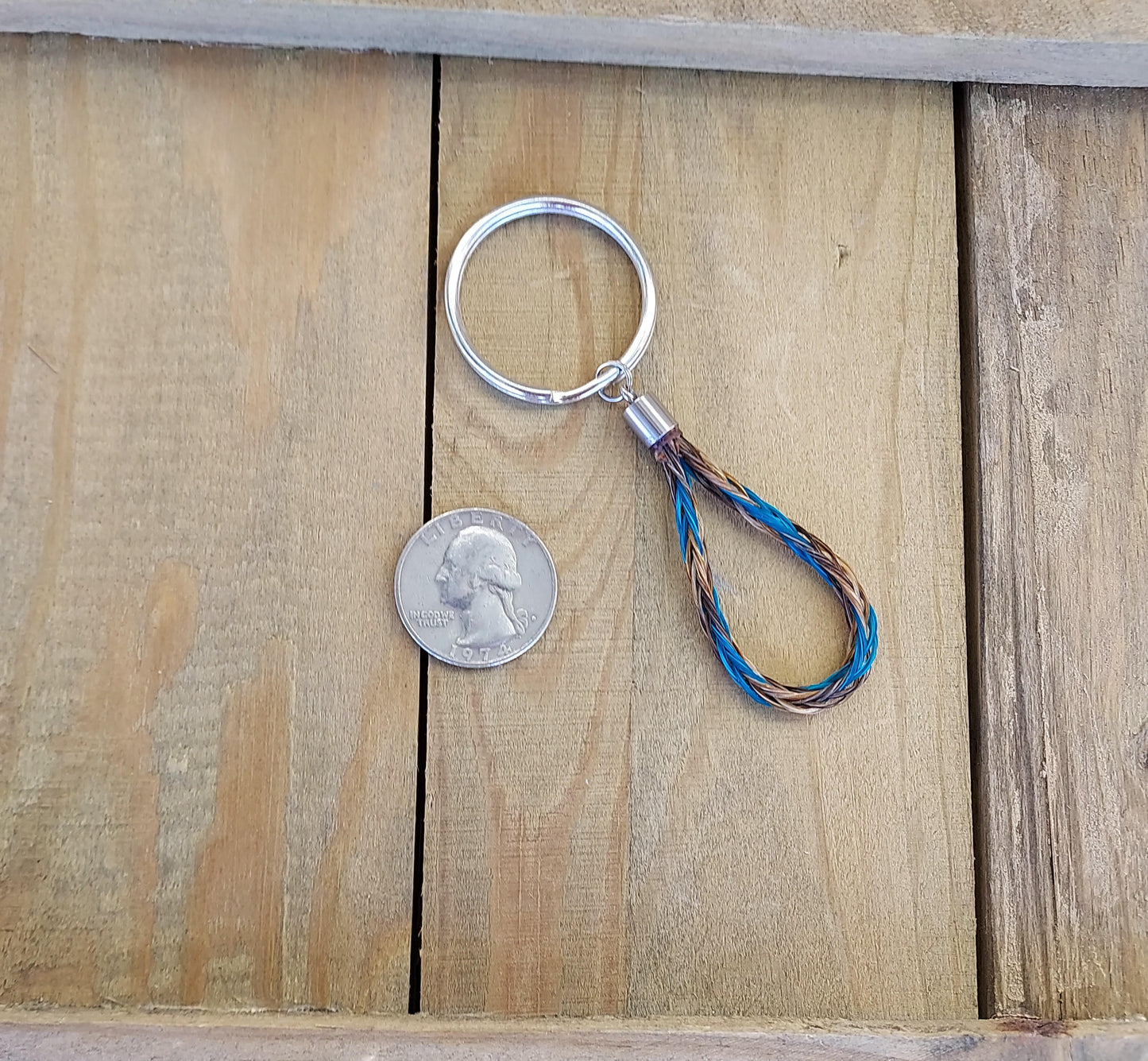 Keychain with braided design next to a coin on wooden surface