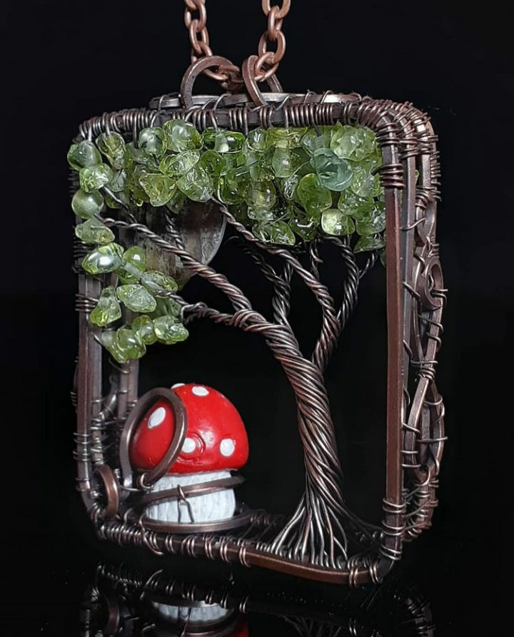 " Into The Woods " Tree Of Life Pendent Artist: Lindsey Griffin Peridot bead tree leaves and Mother of Pearl moon with cute little mushroom on the ground  3-D pendant in oxidized copper  Brown leather cord for wearing as a necklace  2 1/16" Long x 1 9/16" Wide x 1/2" Deep  Care instructions and polishing cloth included  Unique 3-D pendant will be a beautiful statement piece for any wardrobe