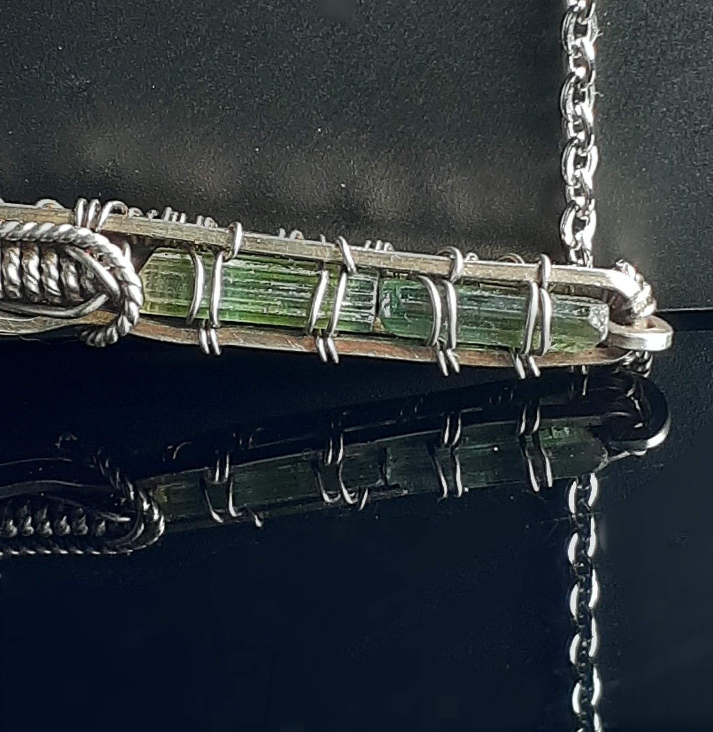 Blue Barite from the Rocky Mountains wrapped to make up the stock of the shotgun Green Tourmaline wrapped make up the barrel of the shotgun Silver filled wire wrapping make this a very unique shotgun pendant design 1/2" long x 3" wide x 1/8" deep Silver chain with lobster clasp