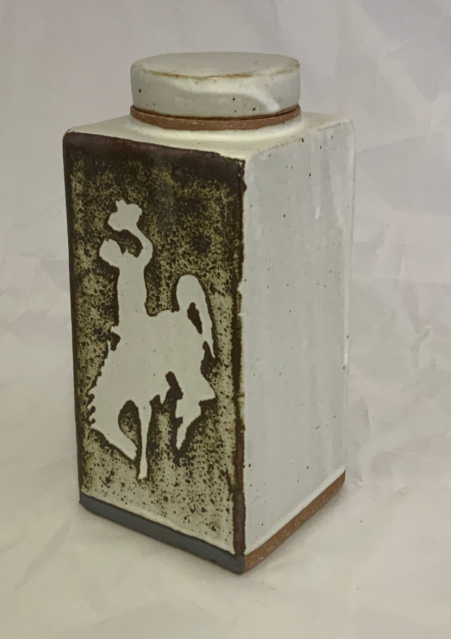 Medium Ceramic Rectangle Stoneware Bucking Horse Jar Muffy Moore Ceramic Potter Rectangle Bucking Horse Jar 2.5" L x 2.5" w x 6" H Stoneware Very Decorative Piece White with Bucking Horse, Steamboat, the UWYO logo. in Brown/White
