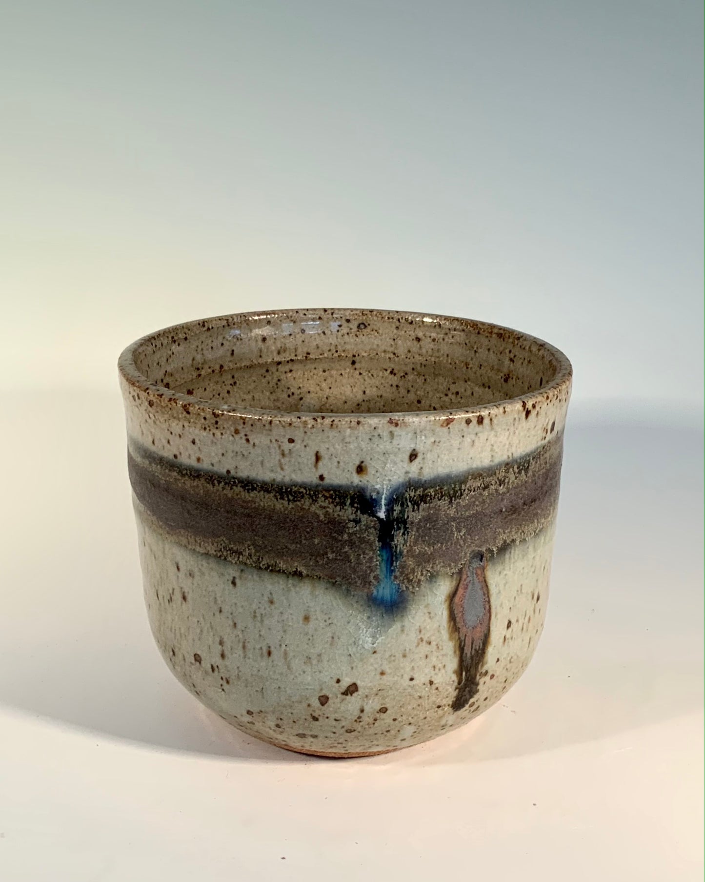 5 inch vase. gray with brown speckles. brown stripe around the toop with hints of blue in the stripe. Large Speckled Stoneware Vase Muffy Moore Ceramic Potter Large gray vase with brown speckles Brown stripe with hints of blue No glaze on bottom of vase 5" wide x 4 1/2" tall Hold small fruit or candy