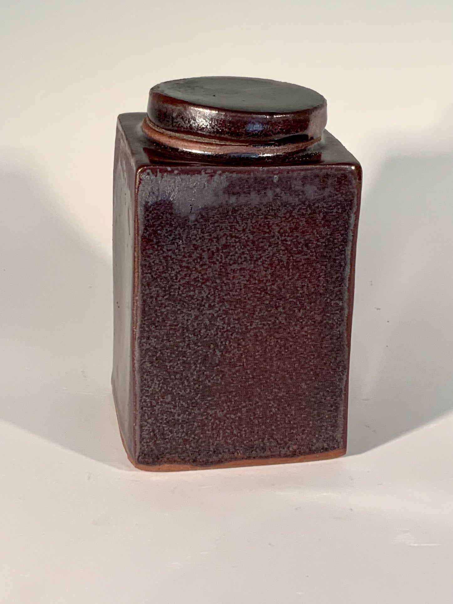 Deep Reddish Brown Stoneware Jar Muffy Moore: Ceramic Potter Small persimmon red square jar 2.75" Long x 2.75" Wide x 5" Deep Dishwasher safe, oven and food safe Great for dried flowers or loose tea and so on Please note Items are handmade by Artist and there is a slight variation from piece to piece