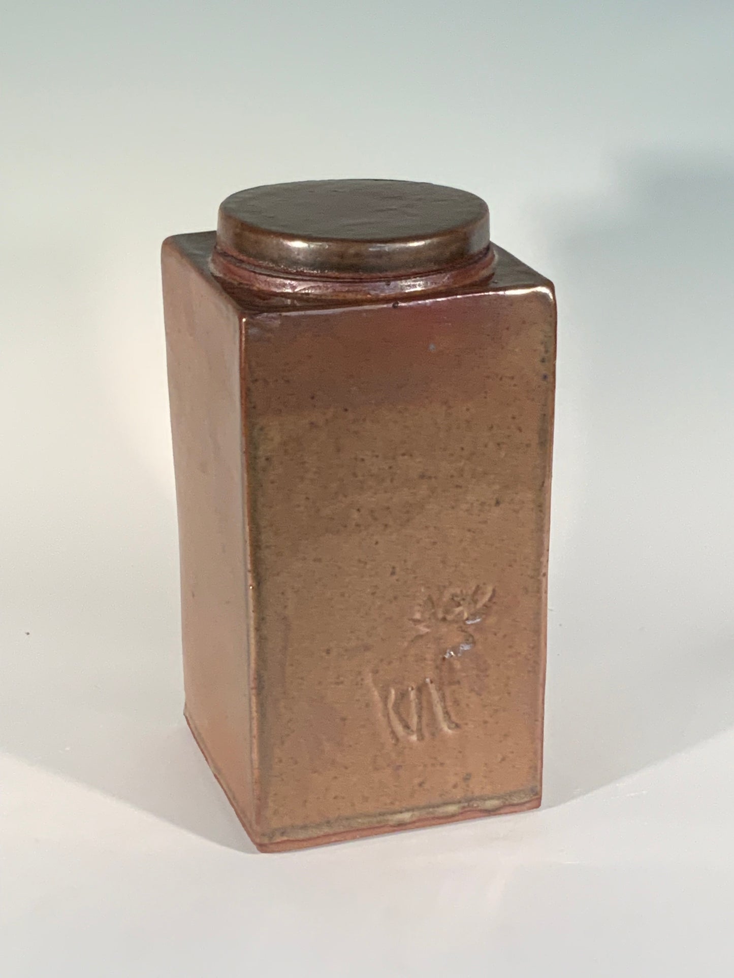 Tall Stoneware Jar Muffy Moore: Ceramic Potter Rectangle slab stoneware jar with lid 3 1/2" Long x 3 1/2" Wide x 7" High Brown glaze Moose stamp on one side Large round opening with lid Find the hidden stamp Dishwasher safe, oven and food safe Would make a nice storage container for dry goods