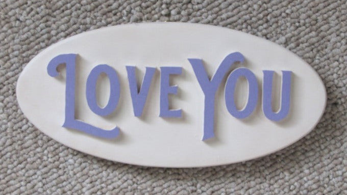 Wooden oval sign with Hand cut letters spelling Love You. eye bolt and chain for hanging the sign.