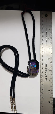 Bolo Tie with Multi Colored Fused Glass Pendant Fused Glass Artist: Leslie Irving  Square dichro custom pendant in purples, black and clear  Geometric, abstract design  Black, soft bolo tie with silver end caps   