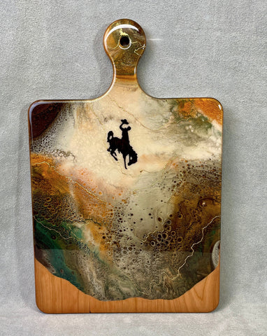 bucking horse and rider decal on a cherry wood cheese board with teal, bronw and cream resin and 24K gold accents