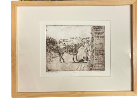 " A Chat On The Road " Cowboy with Dog Framed  Itaglio Etching Artist: Mary Cunningham  Sharing the road with livestock on foot or in a trailer is a common occurrence across the rural West. These less traveled country roads provide the space and safety for cowboys to move livestock to fresh pastures and bring them home for Spring calving and lambing. As the livestock trails down the road the ritual also lends time for friends and neighbors to stop and visit along the way. 
