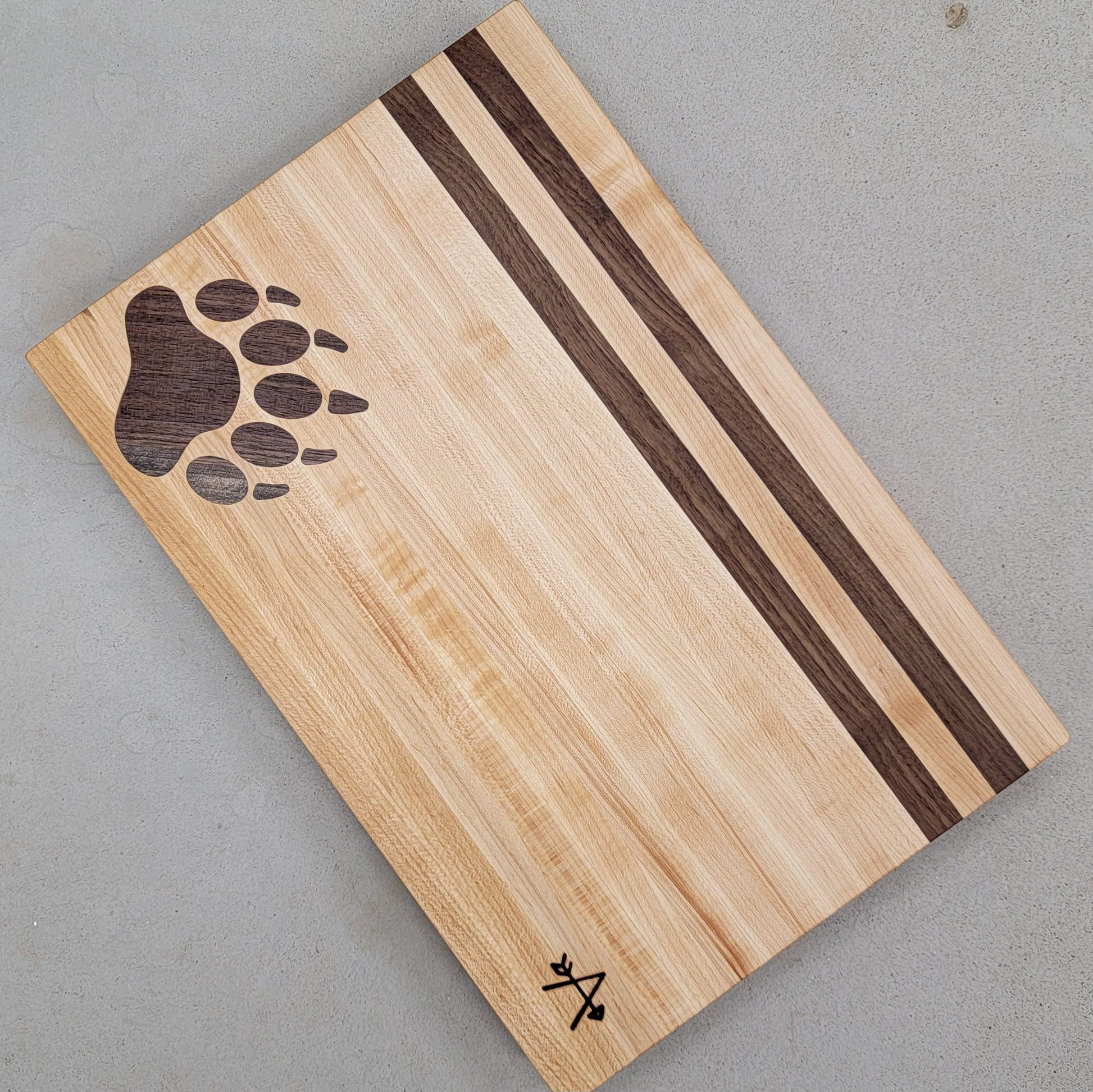 Edge-grain cutting board made of walnut and maple

Bear print inlay in lower left corner