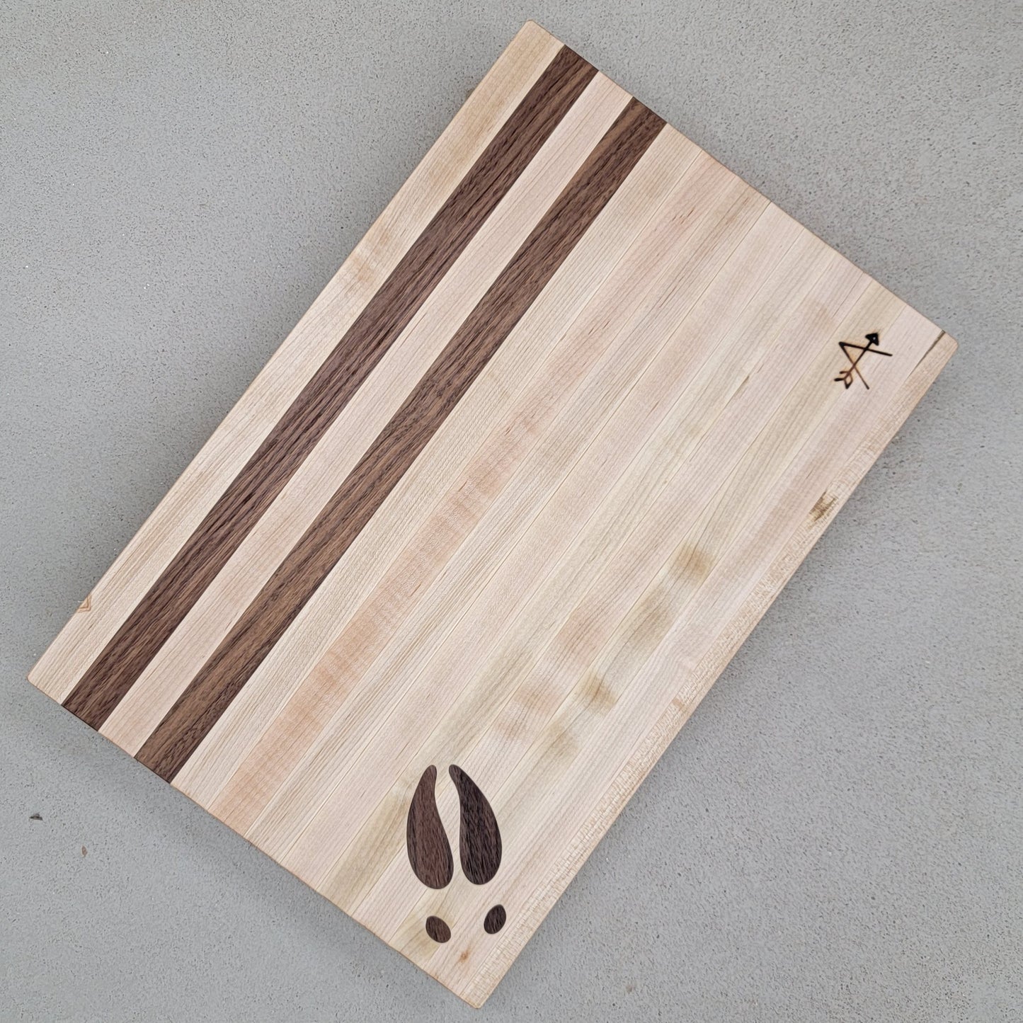" Moose " Maple and Walnut Wood Cutting Board

Artist: Kevin Shimkus

Edge-grain cutting board made of walnut and maple

Moose footprint inlay in lower left corner

Two walnut stripes at the top of board

Has four small feet on bottom side of cutting board to prevent slipping

12" wide by 18" long by 2" deep
Perfect for your entertaining needs and very functional as a cutting board!

8.5 lbs