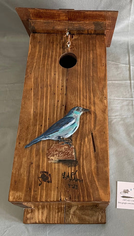  Blue Pine wood with cedar shingle roof and floor  Eye bolt and hook to hold the roof closed, but allow access into the nest box to clean  Cedar roof helps keep out rain and snow  Carved and painted 3-D blue bird on front of box  18" tall x 8" wide x 6 1/2" long