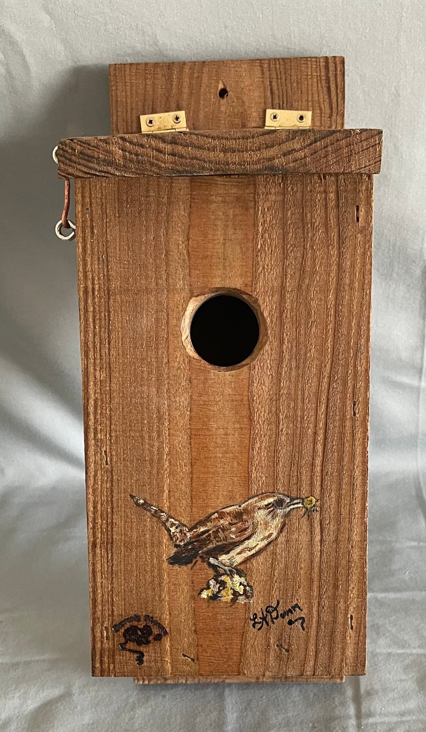 All cedar box, roof and floor with a cute wren painted on front  Hook and eye bolt closure in the roof allows for easy access to clean the box  Two holes drilled into the back board for screws when hanging the box  Wren nesting boxes will also house Chickadees and Finches  14" tall x 5" wide x 6 1/2" long