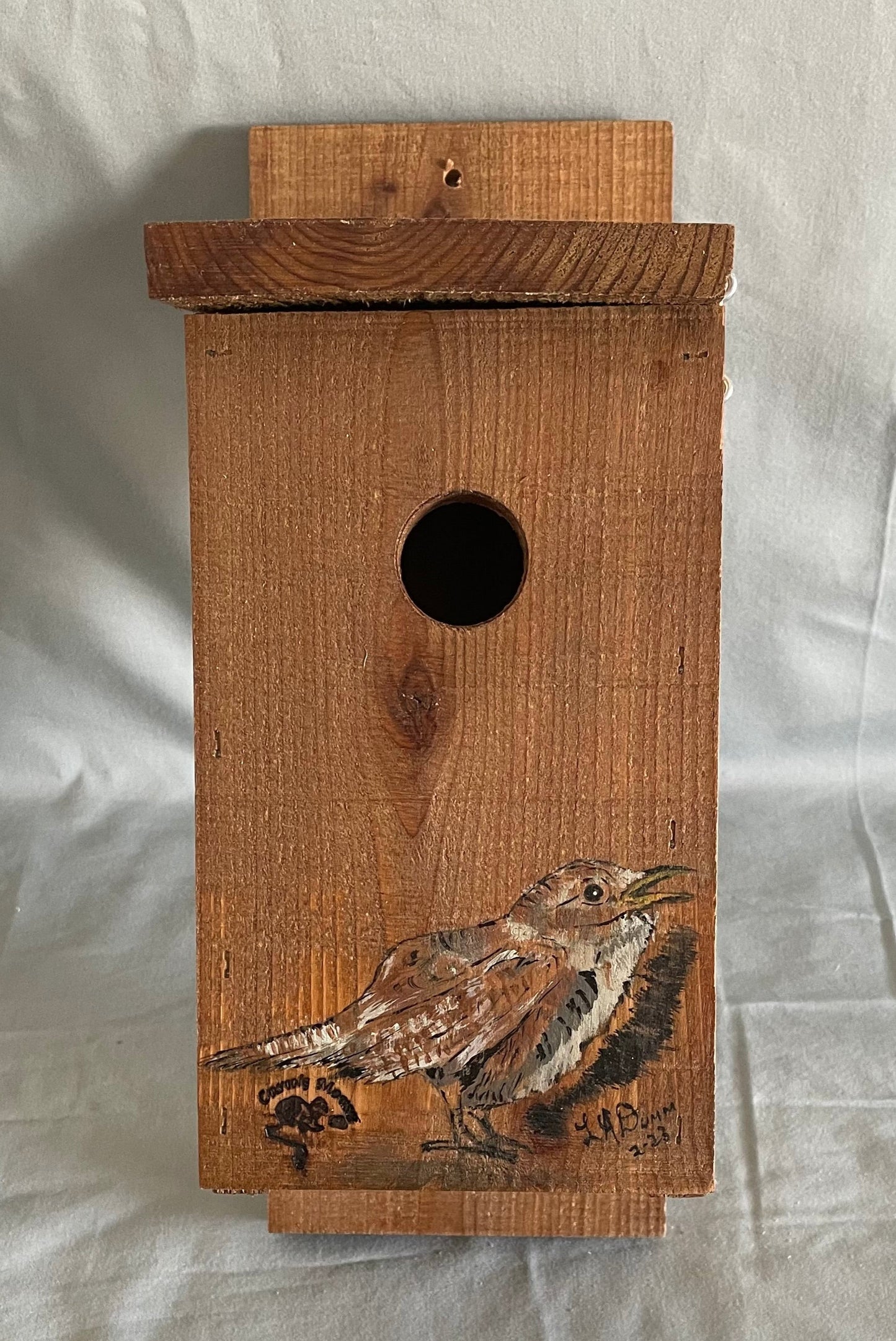 All cedar box, roof and floor with a large wren painted on the front  Hook and eye bolt closure in the roof allows for easy access to clean the box  Two holes drilled into the back board for screws when hanging the box  Wren nesting boxes will also house Chickadees and Finches  14" tall x 5" wide x 6 1/2" long