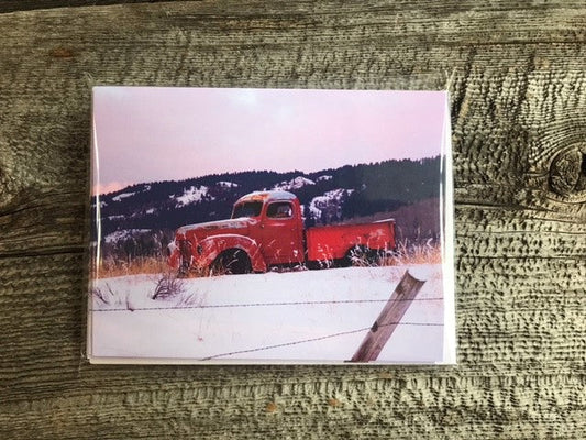 Old Red Truck Greeting Card Four Pack Photographer: Lisa Edwards Old red truck against a dark blue mountain surrounded by snow in a field  Four pack of cards with  envelopes  Nice for greeting cards for all  Blank card  Envelope included   4" wide x 5.5" long