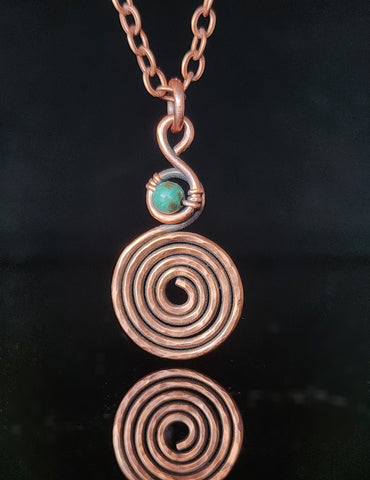 African turquoise bead wrapped in oxidized and hammered copper wire that trails and spirals below the bead  1.26" Long x .68" Wide  Copper chain with lobster clasp closure  A truly one-of-a-kind piece of jewelry  Care instructions with polishing cloth included
