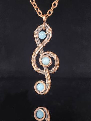 Aquamarine stones wrapped in oxidized copper wire forming a Treble Clef  1.57" Long x .68" Wide  Copper chain with lobster clasp closure  A truly one-of-a-kind piece of jewelry  Care instructions with polishing cloth included