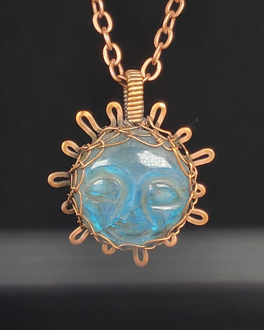 Carved sun face in labradorite wrapped in oxidized copper wire to look like the sun  1.31" Long x 1" Wide  Copper chain with lobster clasp closure  A truly one-of-a-kind piece of jewelry  Care instructions with polishing cloth included  Unique piece to brighten someone's day