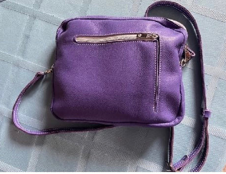 Leather Cross body purse  Long adjustable leather shoulder strap  Large pocket to carry larger items, such as wallets, sunglasses or snacks  External pocket allows easy access to smaller items such as keys  Both pockets are zippered giving the items security  Purple leather stitched with white thread  Use as an everyday purse, or perfect for a night on the town