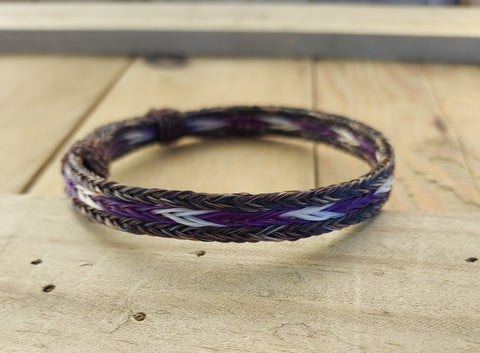 Adjustable Horsehair Bracelet  Dark mix border with purple and white center ( natural and dyed horsehair )  Brown horsehair needle knots for adjusting the bracelet  3/8" wide  Will adjust to fit most wrist sizes 
