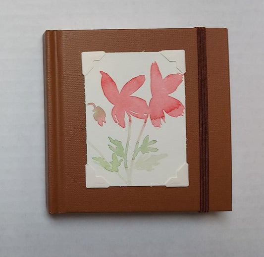 Brown colored mini sketchbook  Brown stretch band helps hold the book closed  Original watercolor of Poppies attached to the cover  Blank pages inside  A great little sketchbook to take with you  Keep in a pocket or bag and take with you when you go  4" x 4" x 3/4"   