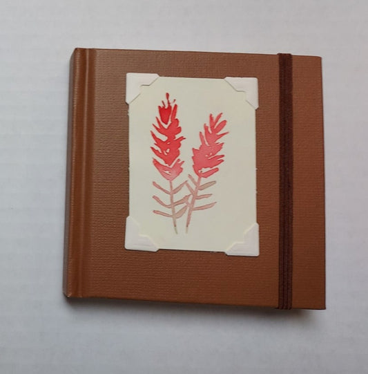 Brown colored mini sketchbook  Brown stretch band helps hold the book closed  Original watercolor of Indian Paintbrush attached to the cover  Blank pages inside  A great little sketchbook to take with you  Keep in a pocket or bag and take with you when you go  4" x 4" x 3/4"