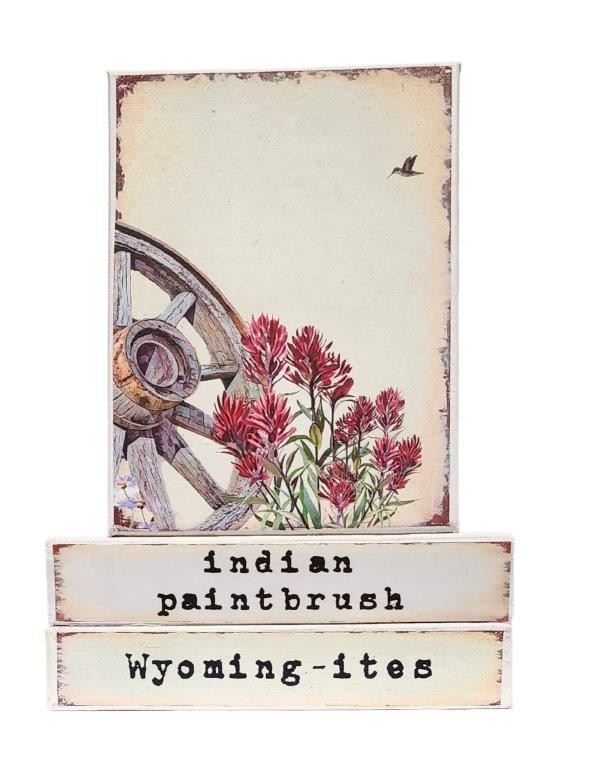 " Indian Paintbrush Wyoming-ites" Canvas Print Artist: Catherine Holt  Print on canvas with wooden framework   Copy from artists original  Indian Paintbrush flower with a wagon wheel, small humming bird in upper right   Indian Paintbrush label on one side and Wyoming-ites label on the other  6" long x 8" high x 1 1/2" wide  Signed and numbered by the artist