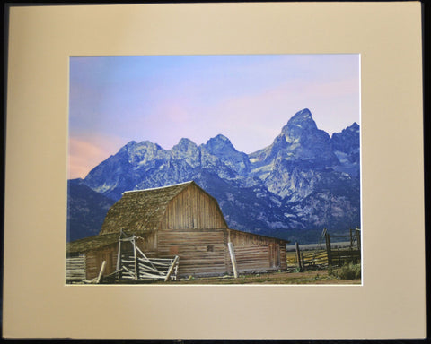 Matted color photograph of the Moulton Barn with the Grand Teton Mountains at sunset  Double matted in a tan and dark brown matting  18" long x 12" high print  20" long x 16" high as matted  In a plastic sleeve and on sturdy foam board for added protection  Ready for a frame or to be displayed on an easel