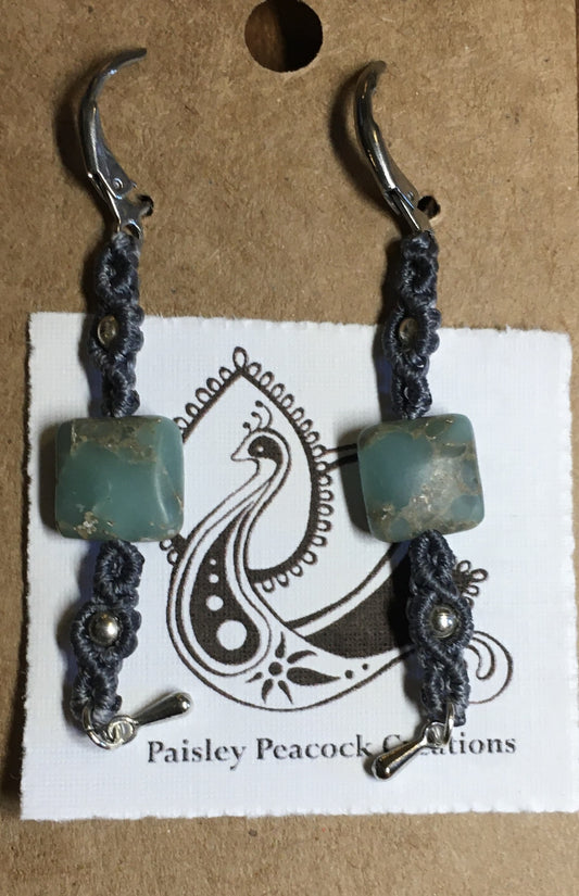 Aqua Sea Sediment Macrame Earrings Artist: Erin Abraham  Square aqua-toned sea sediment stones and silver tone accent beads  Made with lightweight grey nylon cord   201 stainless surgical steel lever backs for comfort  2" long x 3/8" wide One-of-a-kind and will never be duplicated 