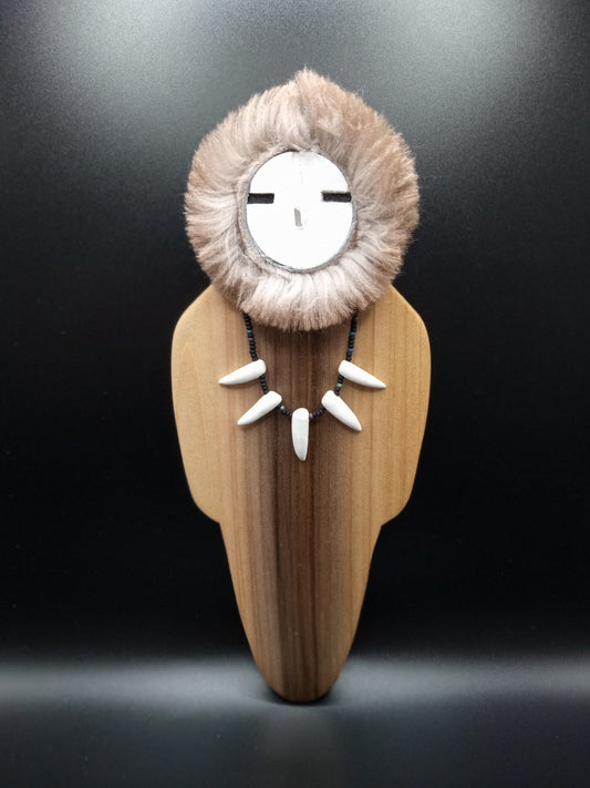 Human like figure with natural wood color  Head surrounded by fur, reminiscent of the native American traditional wear  Figure wearing bead and claw necklace
