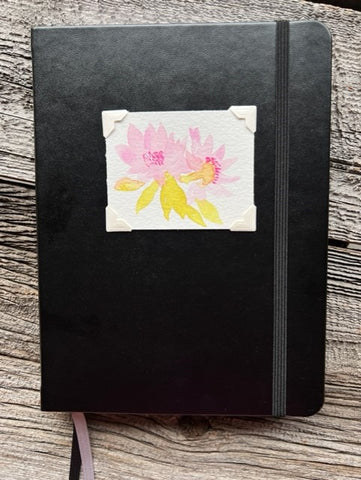 Hardcover black lined journal  Black elastic band helps hold the book closed  Ribbon page marker  Original watercolor of Bitterroot flowers attached to the cover  Lined pages inside  A beautiful journal for young and old alike  6" long x 8" high x 3/4" wide