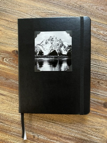 Black cover  Lined journal pages  Black and White Photograph of Mt. Moran in the Grand Teton Mountains attached to the cover  Black elastic strap to hold book secure  Ribbon to mark you pages  Take with you anywhere you go  6" long x 8" high x 3/4" wide
