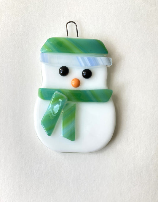 fused glass snowman ornament. Green hat and scarf. blue trim along the bottom of the hat