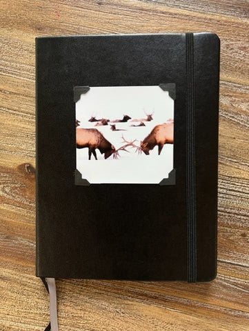 Black cover  Lined journal pages  Photograph of bull elk fighting attached to the cover  Black elastic strap to hold book secure  Ribbon to mark you pages  Take with you anywhere you go  6" long x 8" high x 3/4" wide