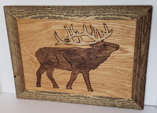 Wood Burned Elk Framed Wall Art Artist: Michael McMahon  Hardwood plywood sanded and burned  Detailed Elk outline stained in walnut  Golden oak background  Polyurethane coated  Rough cut wooden frame stained in brown  Wire hanger on the back  19" long x 14.5" high x .75" wide  Would be perfect for a cabin or for any outdoorsman