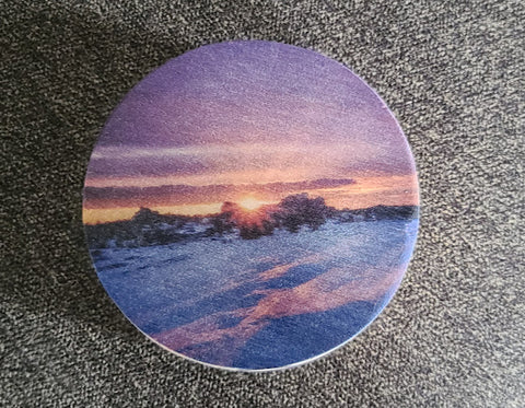 Circular wooden disk with a color photo of the sunrise over a snow covered Vedauwoo  3.5" across x 1/4" wide  Magnet is inset into the wooden disk